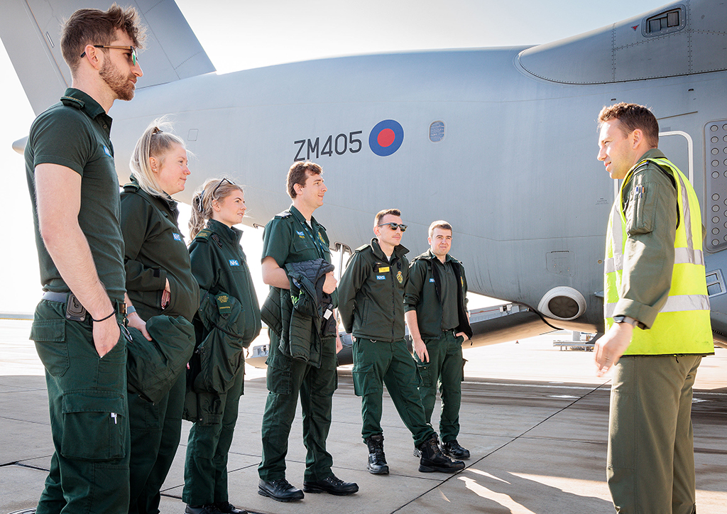 Members of the South Central Ambulance Service receive a briefing, whilst standing outside at the starboard aft area of an Atlas C Mk.1